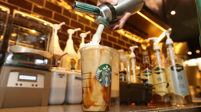 Το Starbucks Barista προσθέτει αφρό σε ένα ποτό μπροστά από σιρόπια
