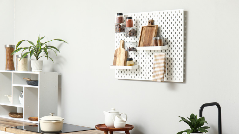 Pegboard που χρησιμοποιείται για μπαχαρικά, κοπτικές σανίδες και πετσέτα πιάτων σε ουδέτερη κουζίνα